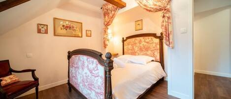 Une chambre à coucher avec un lit en bois, une chaise et un lustre.