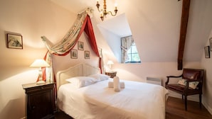 A bedroom with a large bed, two bedside lamps, a chair, and a window with curtains. - The Hôtel de Beaumont carriages (Valognes)