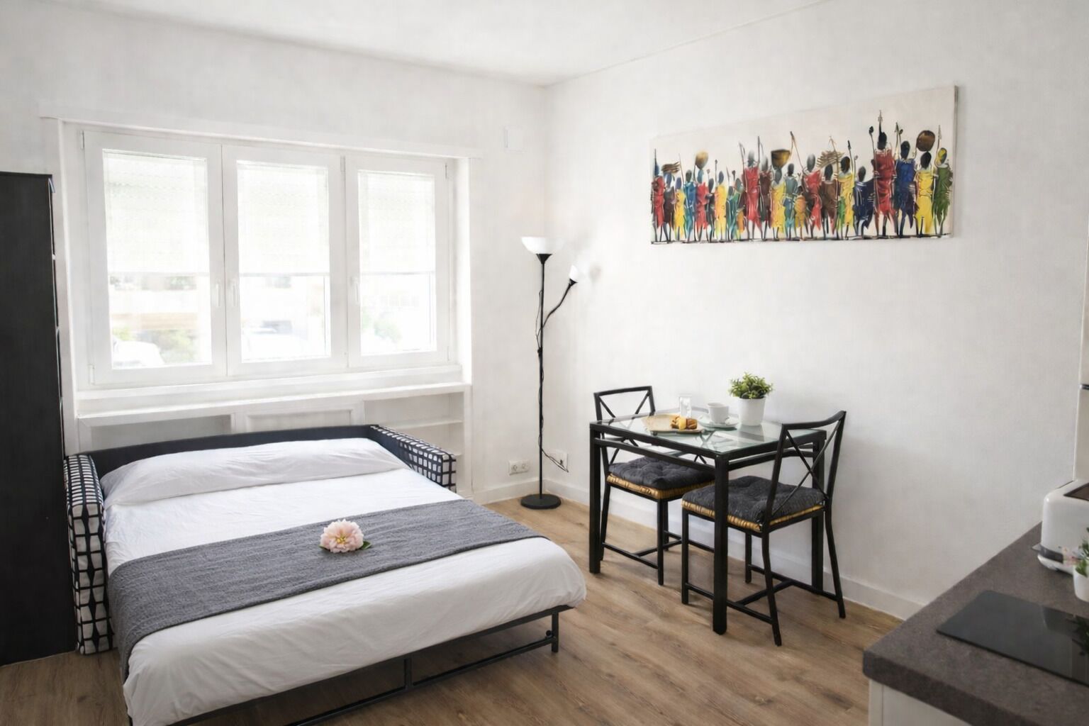 A modern bedroom with a bed, bedside table, chair, and a painting on the wall.