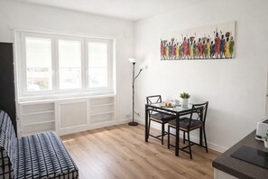 A modern kitchen with a dining area, a large window, and a wall-mounted artwork. - Nestop Colli Albani (Rome)
