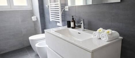 A modern bathroom with a white sink, a mirror, and a towel with flowers.