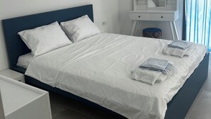 Un dormitorio moderno con cama, mesita de noche, cómoda y tocador con espejo.