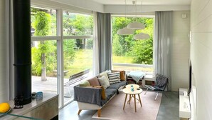 A modern living room with a large window, a sofa, a coffee table, and a fireplace.