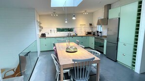 A modern kitchen with a skylight, a dining table with chairs, and a refrigerator.