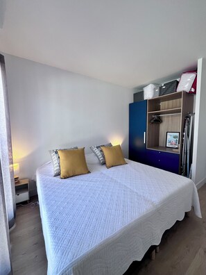 Ein Schlafzimmer mit einem Bett, zwei Kissen, einem Nachttisch, einer Kommode und einem Spiegel.