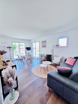 Un salon moderne avec un canapé gris, une table basse ronde et un coin repas comprenant des chaises et une table.