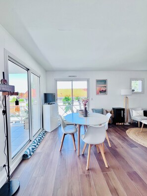 Ein modernes Wohnzimmer mit Essbereich, großen Fenstern und Blick ins Freie.