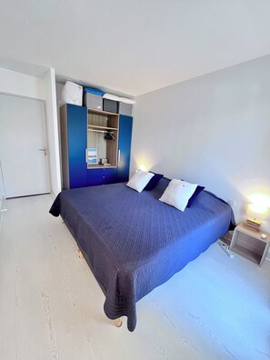 Une chambre à coucher avec un grand lit, une armoire, une table de chevet avec une lampe et une porte.