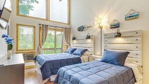 Ein Schlafzimmer mit zwei Betten, einem Schreibtisch, einem Fenster mit Vorhängen und Wanddekoration.