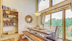Ein Essbereich mit einem Holztisch, weißen Stühlen und einem Bücherregal voller Bücher.