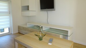 Una cocina moderna con encimera de madera, un lavamanos de vidrio y un televisor empotrado.