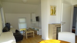 Una sala de estar moderna con una mesa de comedor de madera, un sofá, un televisor y un cuadro en la pared.