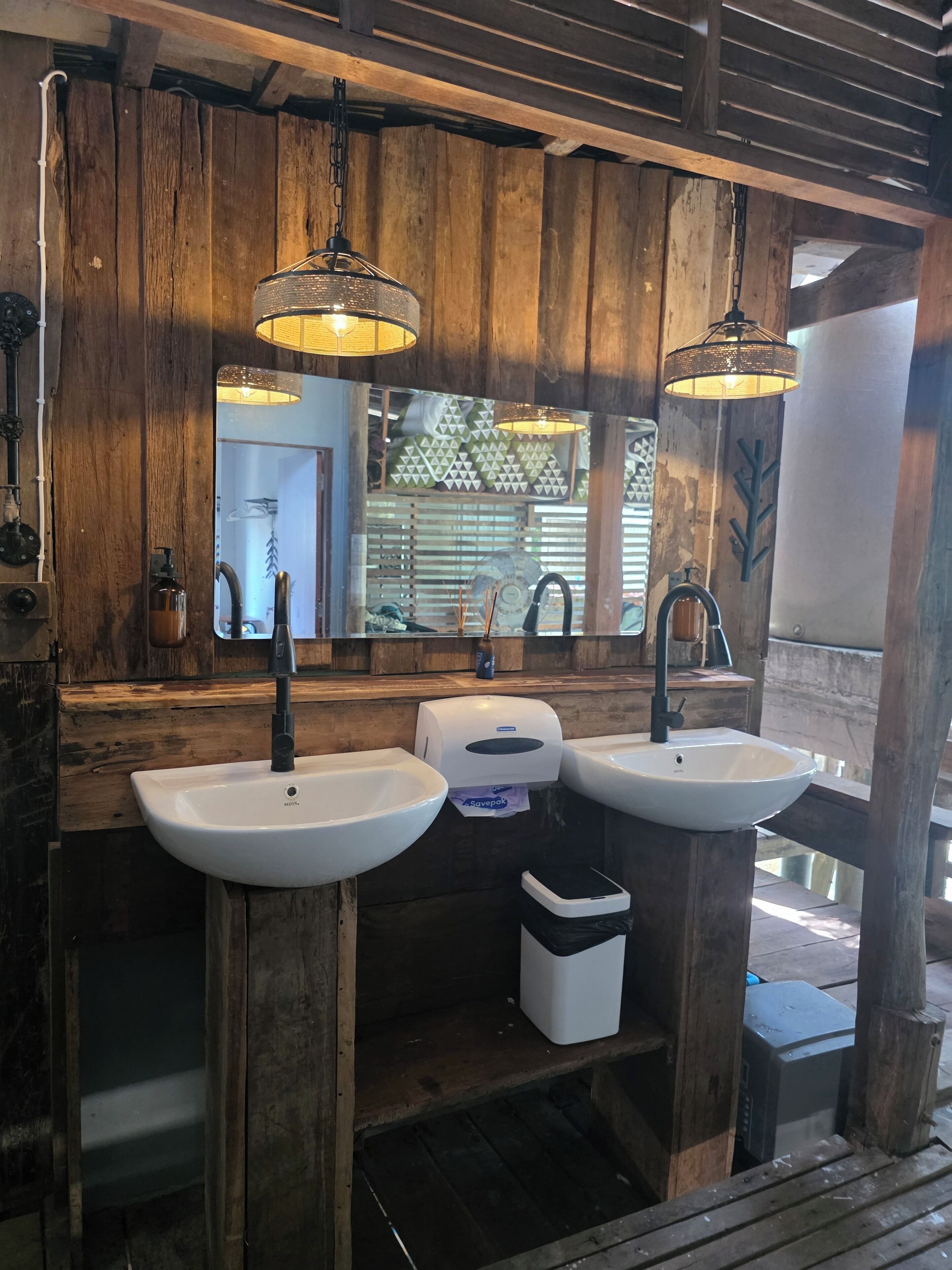 A rustic bathroom with wooden walls and two sinks.