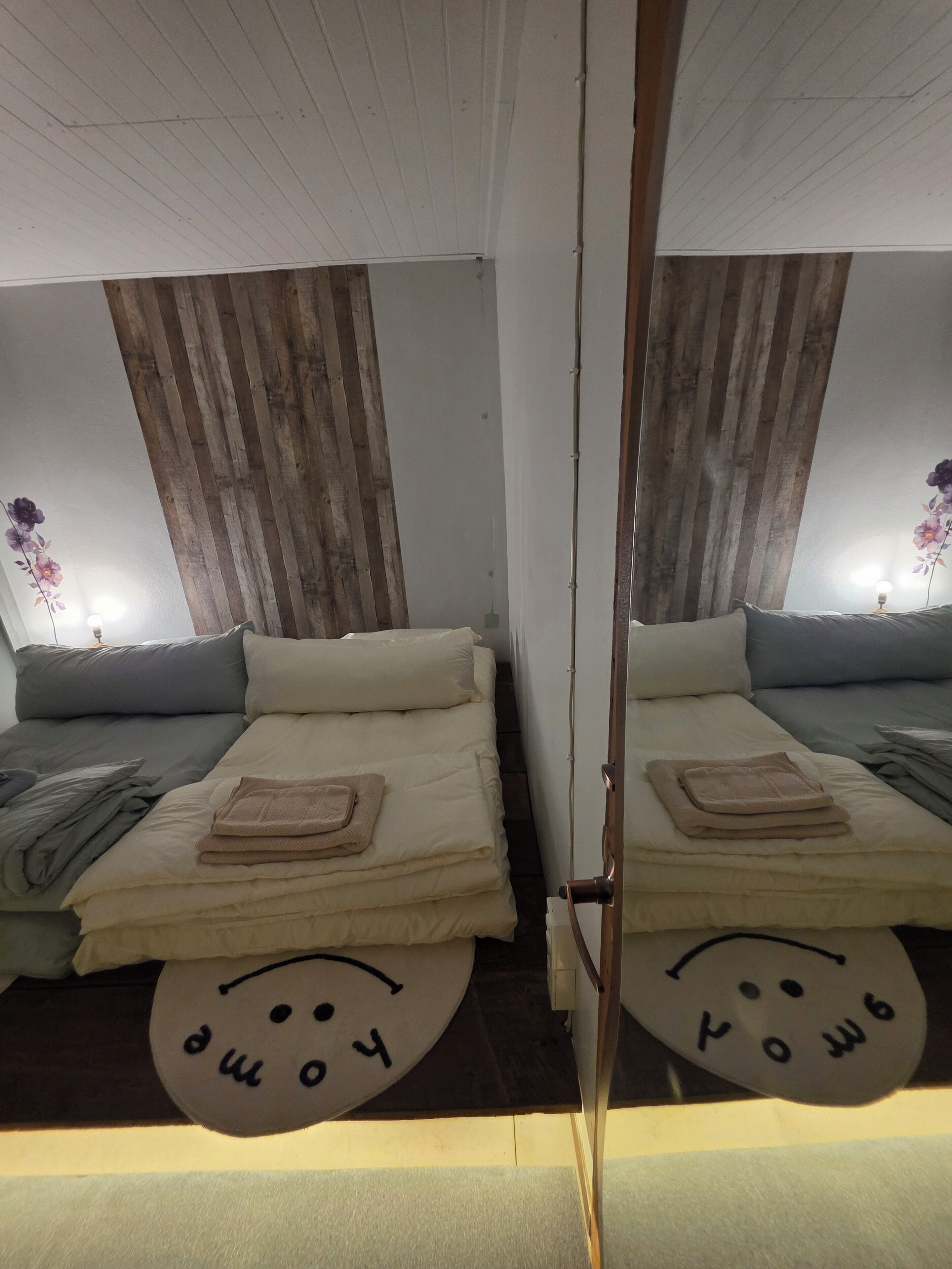 Habitación con espejos, dos camas, cada una con una almohada y una toalla doblada.