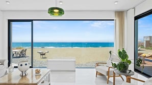 Una sala de estar moderna con un gran ventanal que da a una vista de la playa.