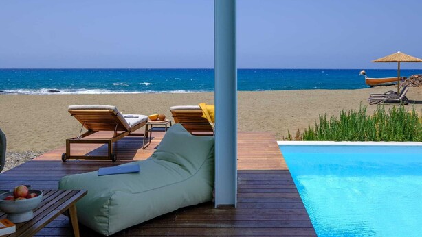 Una terraza de madera con sillones de descanso y una piscina.