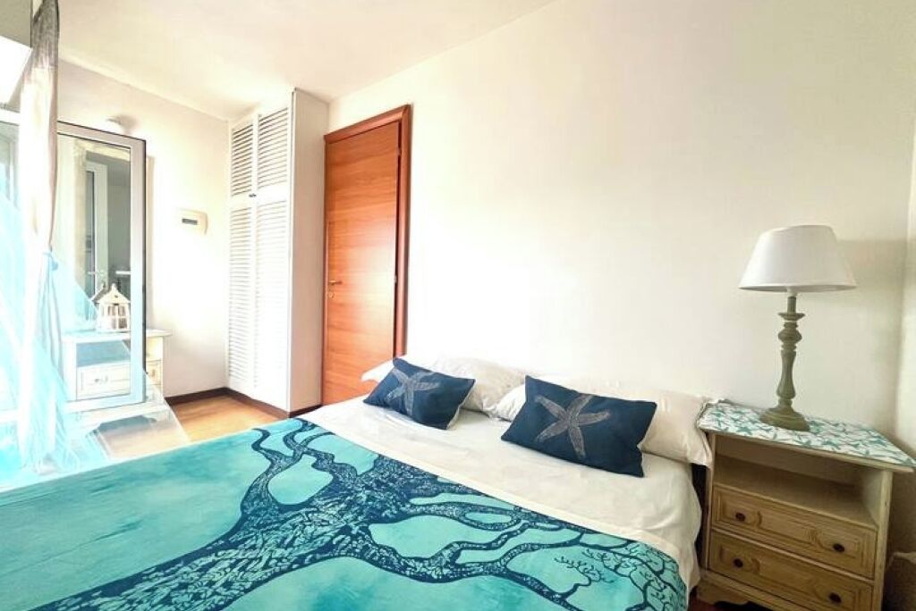 Une chambre à coucher avec un lit, une table de chevet, une lampe et une vue sur la salle de bain.