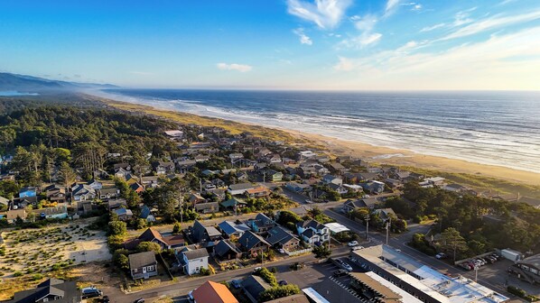 Vista aérea de una zona residencial costera con casas, una playa y un cielo despejado.