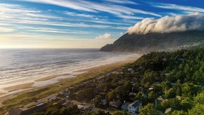 Un pueblo costero con casas a lo largo de la playa, un cielo despejado y una montaña al fondo.