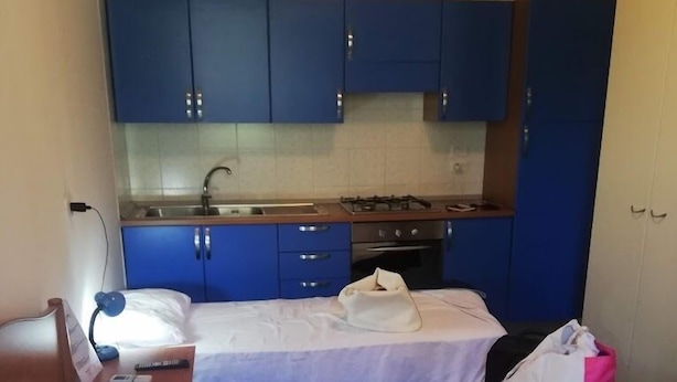 A small, compact room with two beds, a kitchenette with blue cabinets, and a white door. - Exclusive Flats inside 4 Stars Resort (Laura)