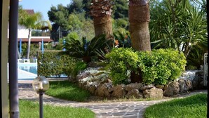 A stone pathway leading through a landscaped garden with palm trees and shrubs. - Exclusive Flats inside 4 Stars Resort (Laura)