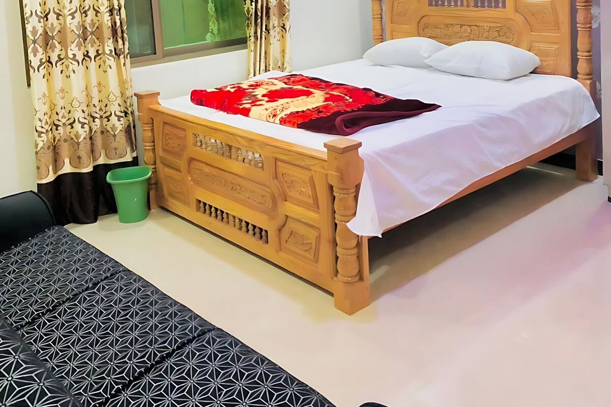 Un dormitorio con cama de madera, cortinas estampadas, un cubo verde y una pared azul con diseño.