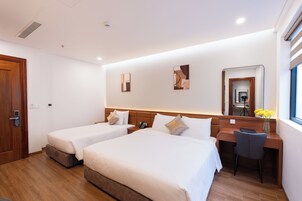 Habitación de hotel con dos camas, un escritorio y una silla. Hay dos cuadros en la pared y un espejo sobre el escritorio.