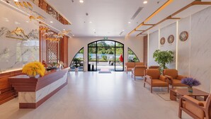Um hall de hotel moderno com balcão de recepção, área de estar e grande entrada em arco.