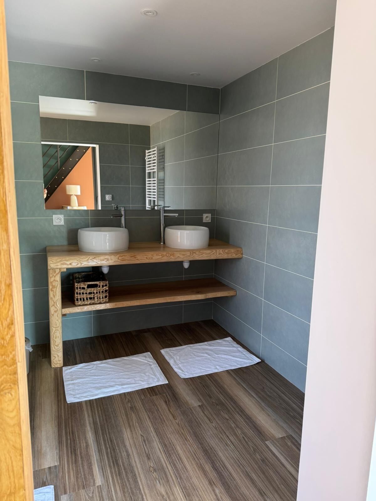 A modern bathroom with two sinks, a wooden vanity, and a mirror.