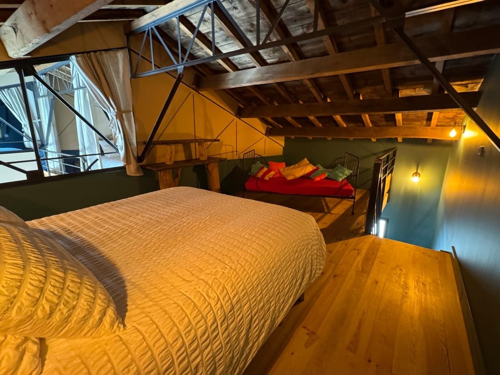 A bedroom with a bed, a red couch, and a staircase.