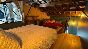 A bedroom with a bed, a red couch, and a staircase.