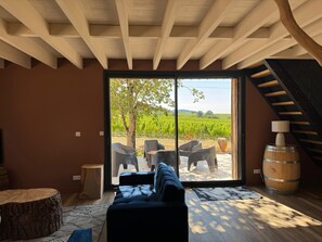 Un interior moderno con un gran ventanal corredero que da a vistas de un viñedo al aire libre.