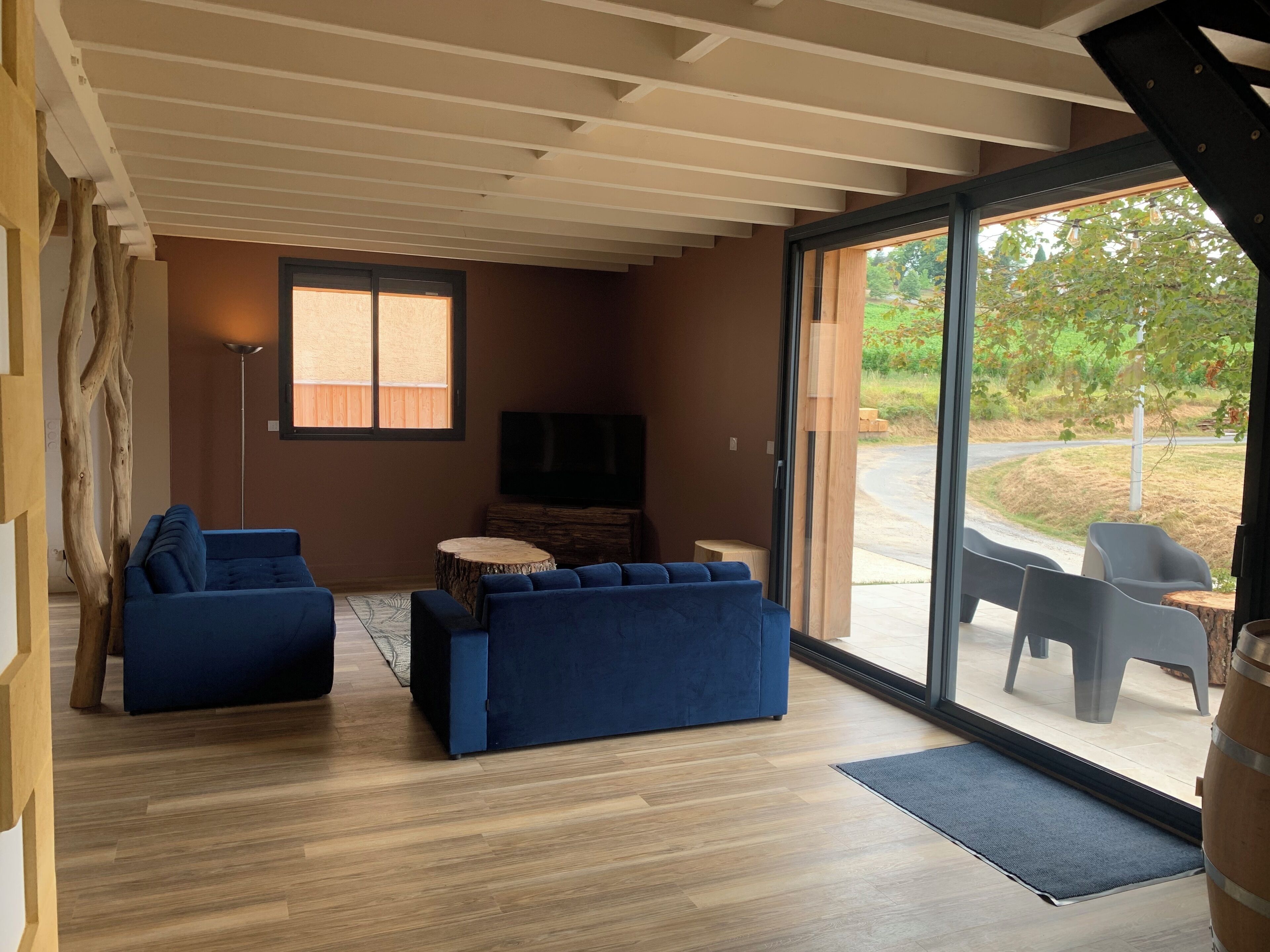 A modern living room with a blue sofa, a round wooden table, and a TV on the wall.