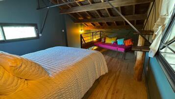 A bedroom with a bed, a hanging chair, and a staircase.