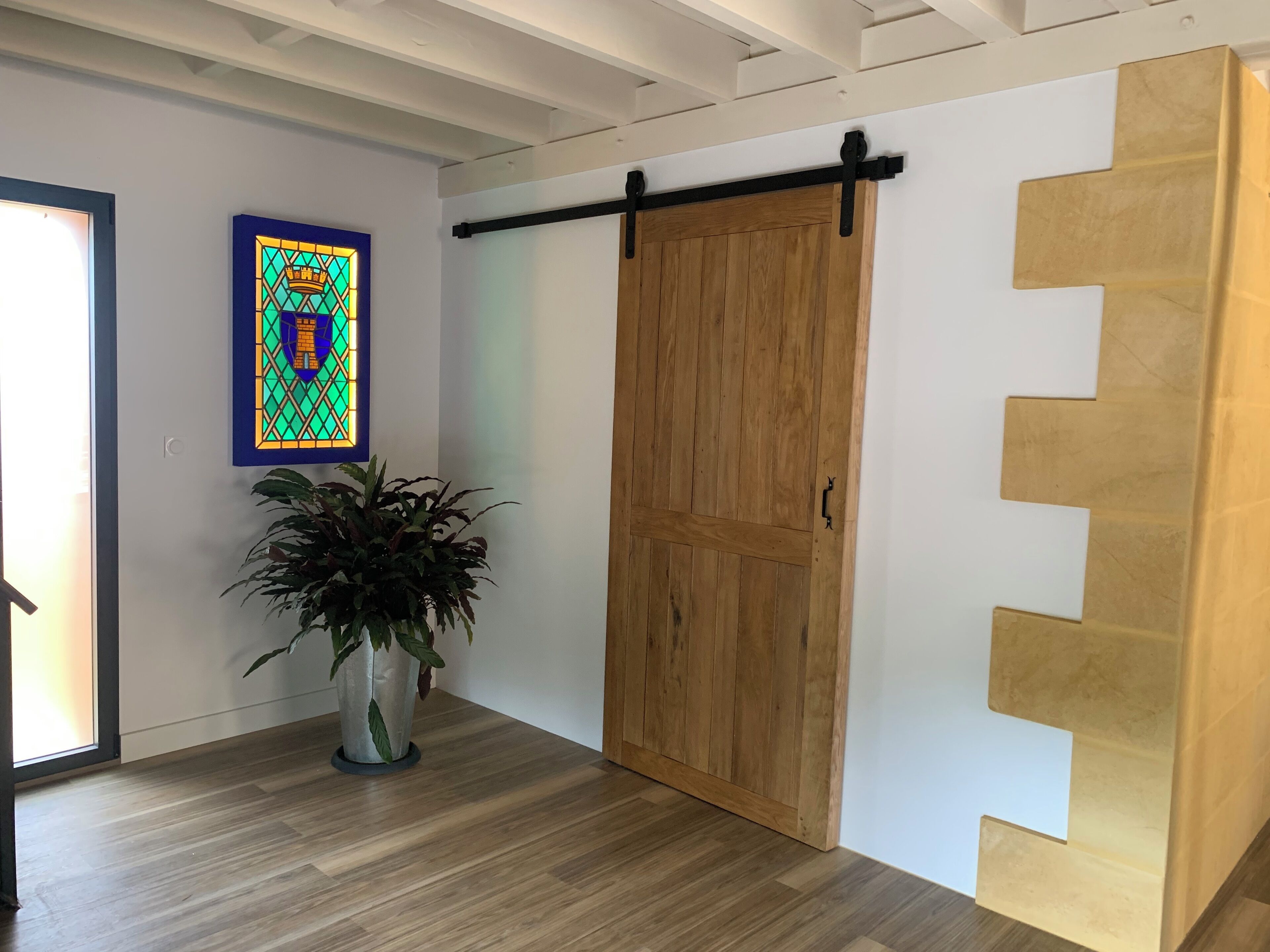 Ein Zimmer mit Holztür, Blumentopf und einem farbenfrohen Bild an der Wand.