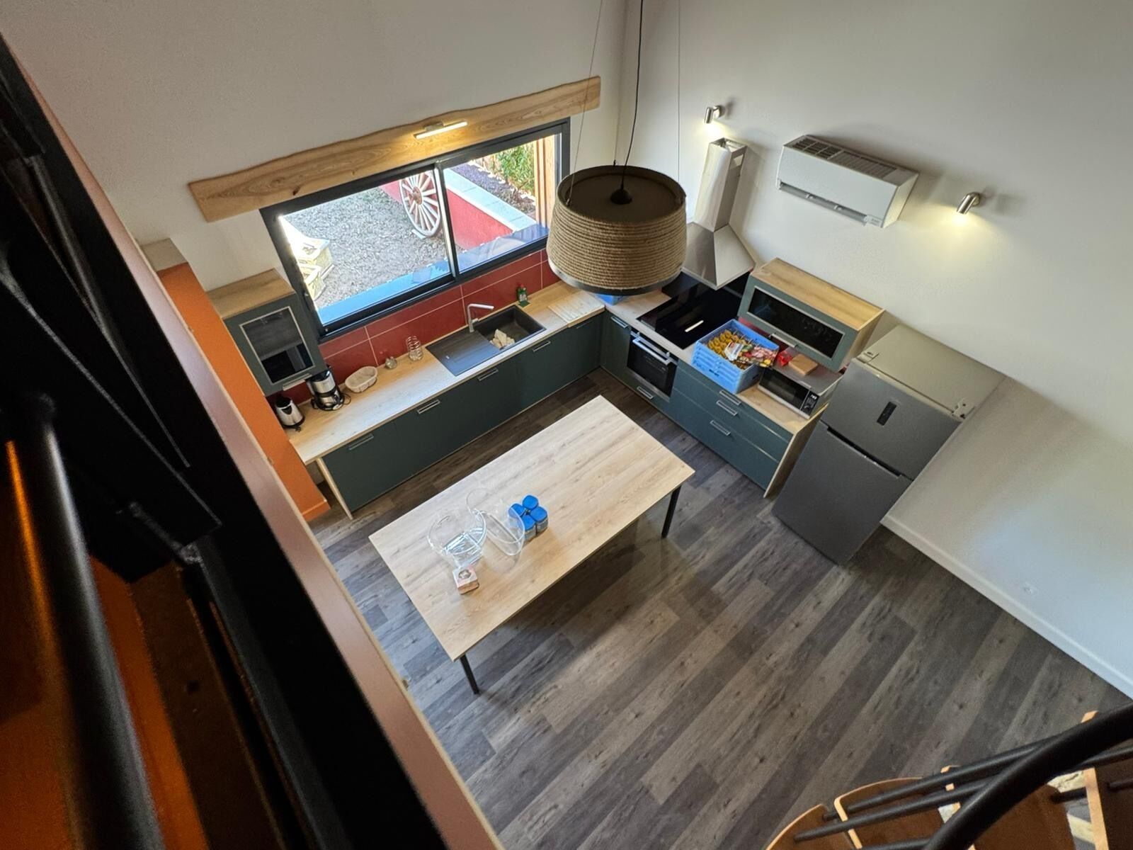 A modern kitchen with a large window, a hanging light fixture, and a built-in oven.