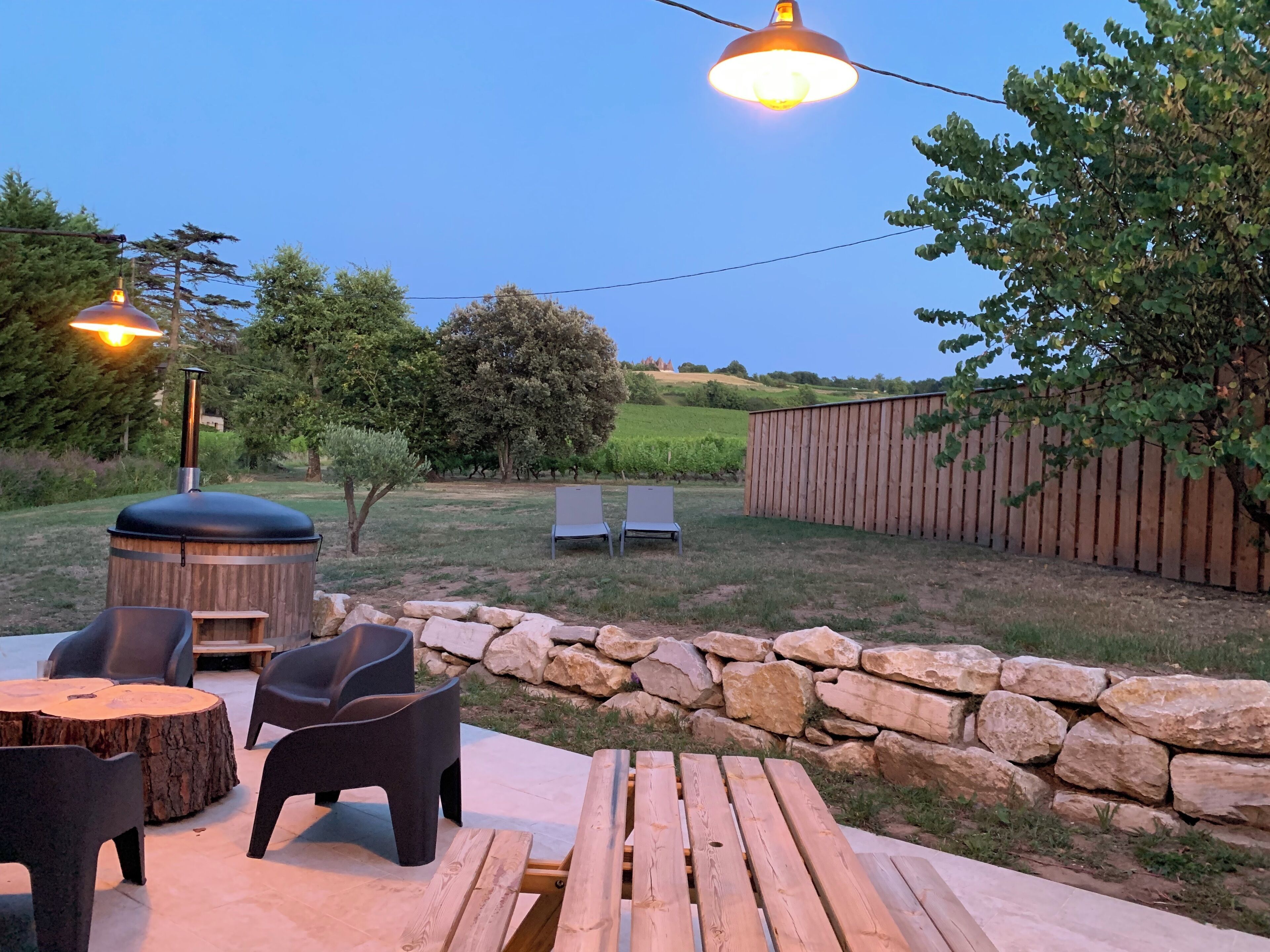 Eine Außenpatio-Terrasse mit einer Steinmauer, Holzbanken und einem Grill.