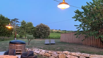 Eine Außenpatio-Terrasse mit einer Steinmauer, Holzbanken und einem Grill.