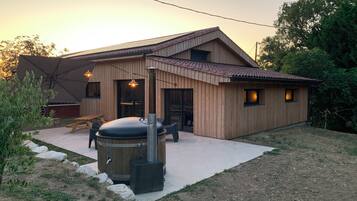 Une maison en bois dotée d’un patio, d’un barbecue et d’un coin repas.
