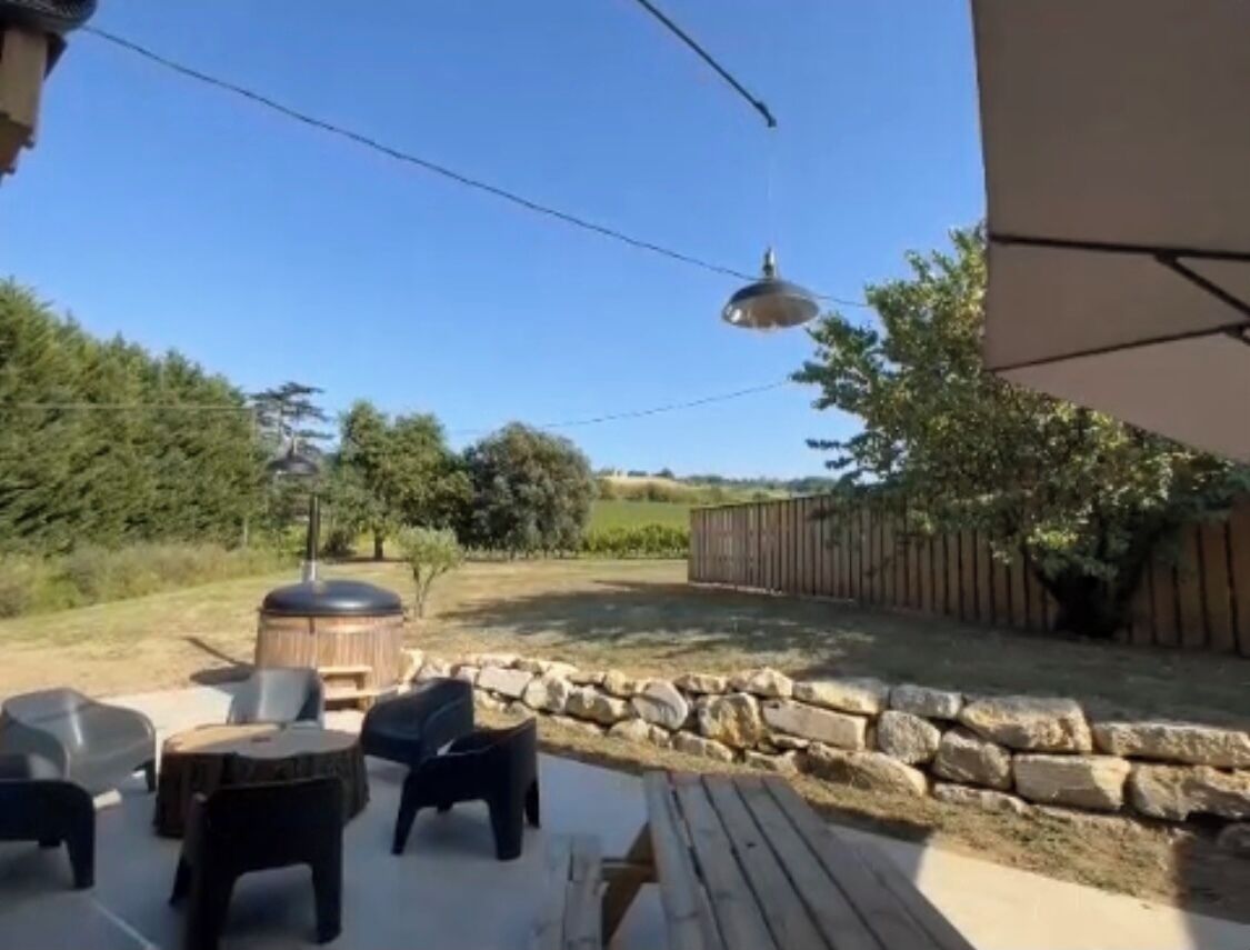 Eine Terrasse im Freien mit Steinmauer, Holzdeck und Gartenmöbeln.