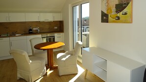 A modern kitchen with white cabinets, a wooden countertop, and a dining area with a wooden table and two chairs. - Sunny house with 2 residential units, large garden and sun terrace (Postmünster)