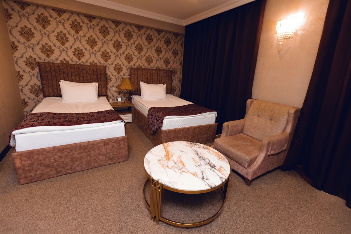 Une chambre d’hôtel avec deux lits, une table basse ronde et une chaise.