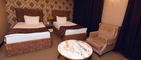 Une chambre d’hôtel avec deux lits, une table basse ronde et une chaise.