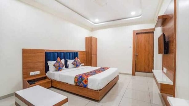 A bedroom with a bed, bedside tables, a wardrobe, and a TV. - Hotel Akshar Palace (Vadodara)