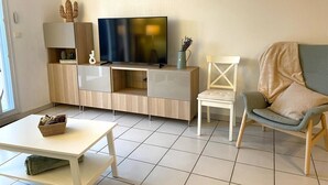 Una sala de estar moderna con una televisión de pantalla plana, un sofá, una mesa de centro y un mueble de televisión con espacio de almacenamiento.
