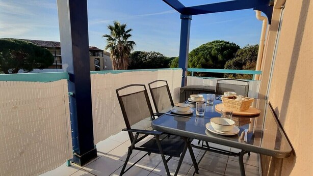 Un balcón con mesa para dos, sillas y una mesa de vidrio.