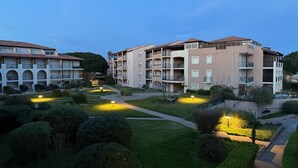 Un hôtel à plusieurs étages, doté de balcons, d’un jardin aménagé et offrant une vue sur un ciel dégagé.