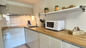 Een moderne keuken met witte kasten, een houten aanrecht, een magnetron en een spoelbak.