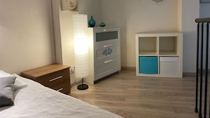 Een slaapkamer met een bed, een houten nachtkastje, een witte ladekast, een smaragdgroene kast en een visdecoratie aan de muur.