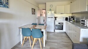 A compact kitchen with a dining area, white cabinets, a refrigerator, an oven, and a microwave.